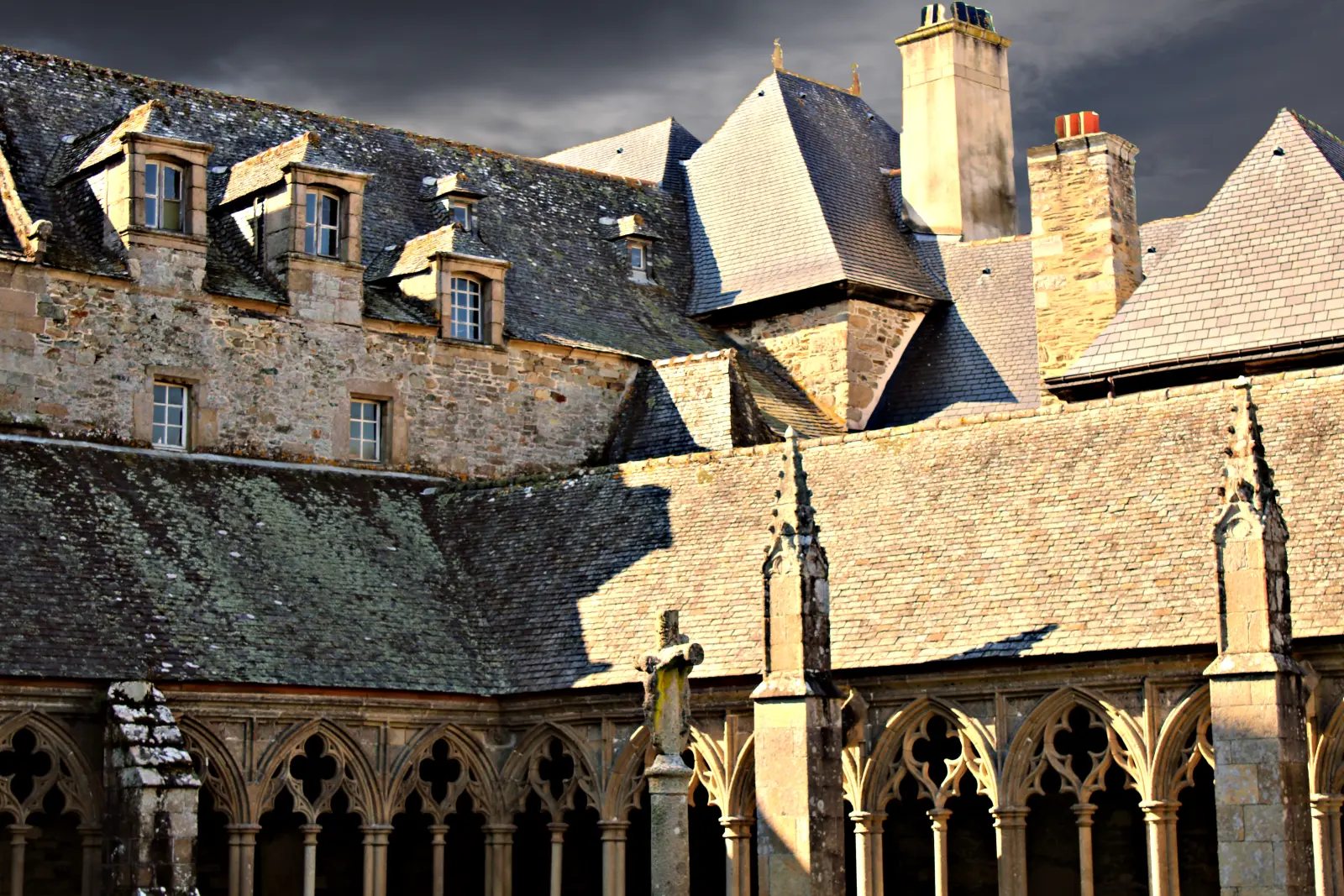 Cloister of Tréguier Cathedral in Brittany, France with medieval stone arches and dramatic sky