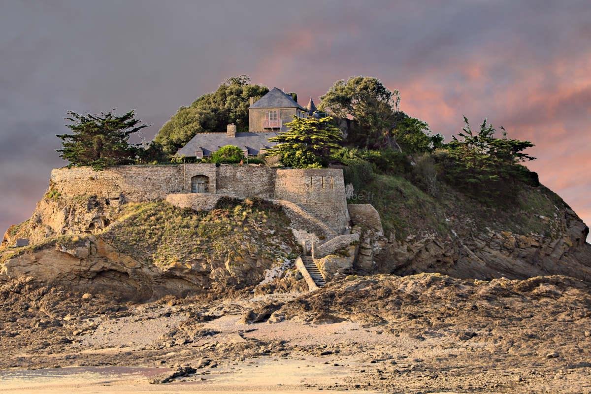 Dramatic sunset over Fort du Guesclin in Brittany, France. A historic island castle glowing under a vibrant orange and pink sky at low tide. Warm coastal landscape photography for home decor.