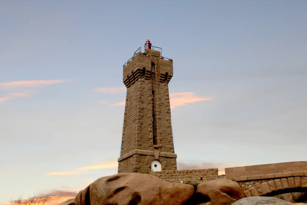 Granite lighthouse standing on rocks at sunset under a pastel sky in Brittany